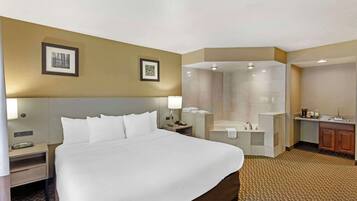 A hotel room with a large bed, a shower area, a vanity with a sink, and two framed pictures on the wall.