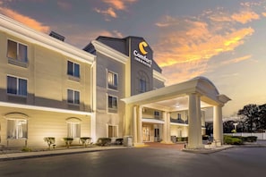 A hotel with a modern design, featuring a prominent 'Comfort Inn & Suites' sign, a covered entrance, and a well-maintained exterior.