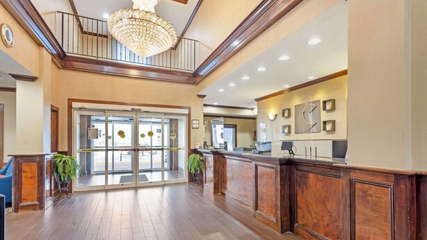A spacious lobby with a wooden reception desk, a chandelier, and a staircase. - Comfort Inn & Suites Carneys Point - Pennsville (Penns Grove)