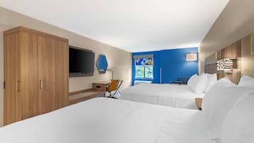 Habitación de hotel con dos camas, un escritorio, una silla, un televisor y una ventana con vistas.