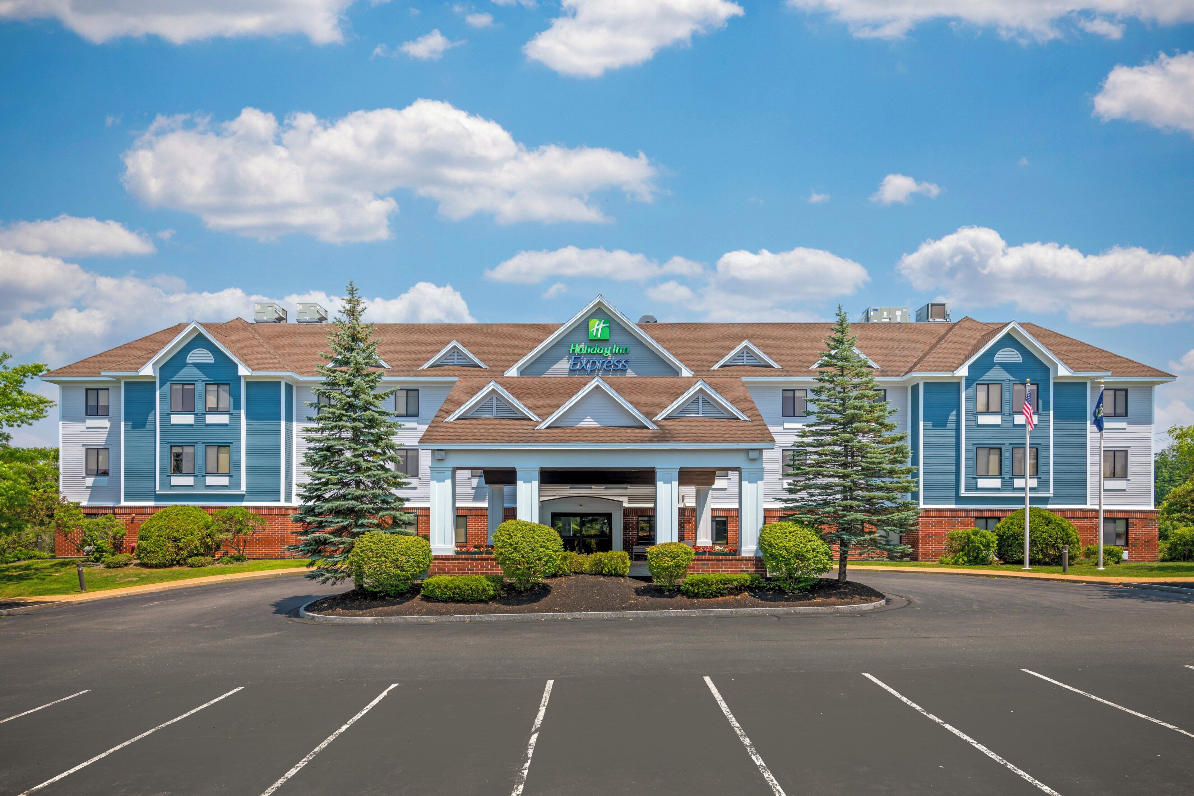 A Holiday Inn Express hotel with a central entrance, two flagpoles, and a parking lot in front.