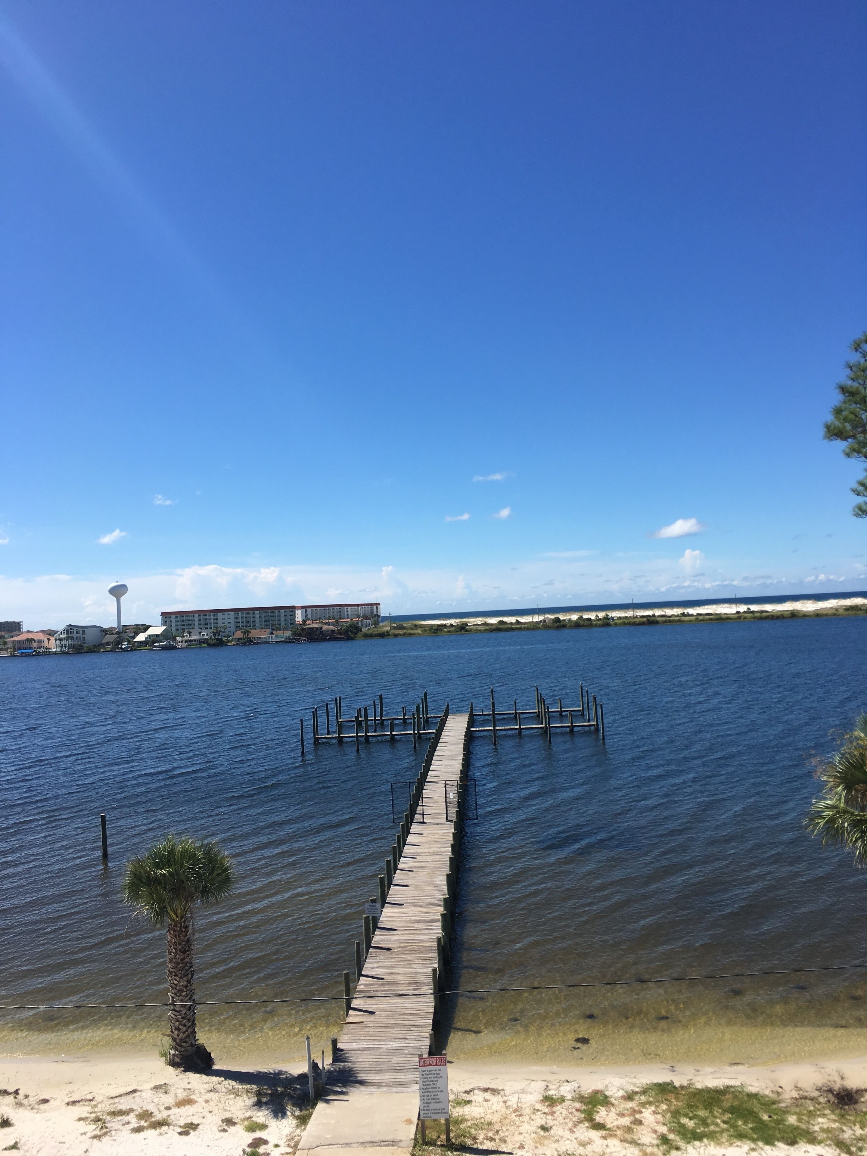Un muelle de madera que se adentra en una masa de agua tranquila, bajo un cielo despejado.