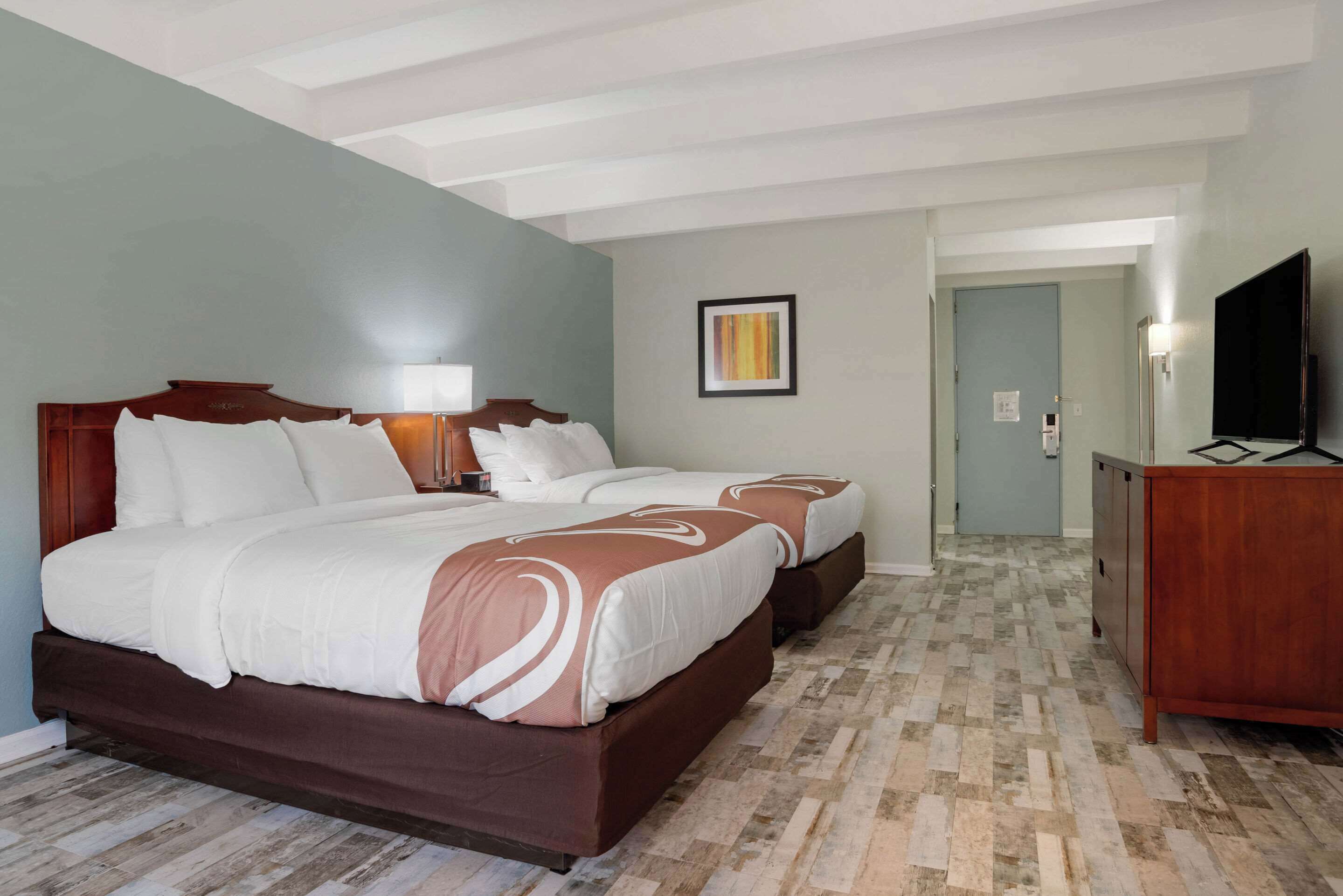 A hotel room with a large bed, a TV, and a desk.