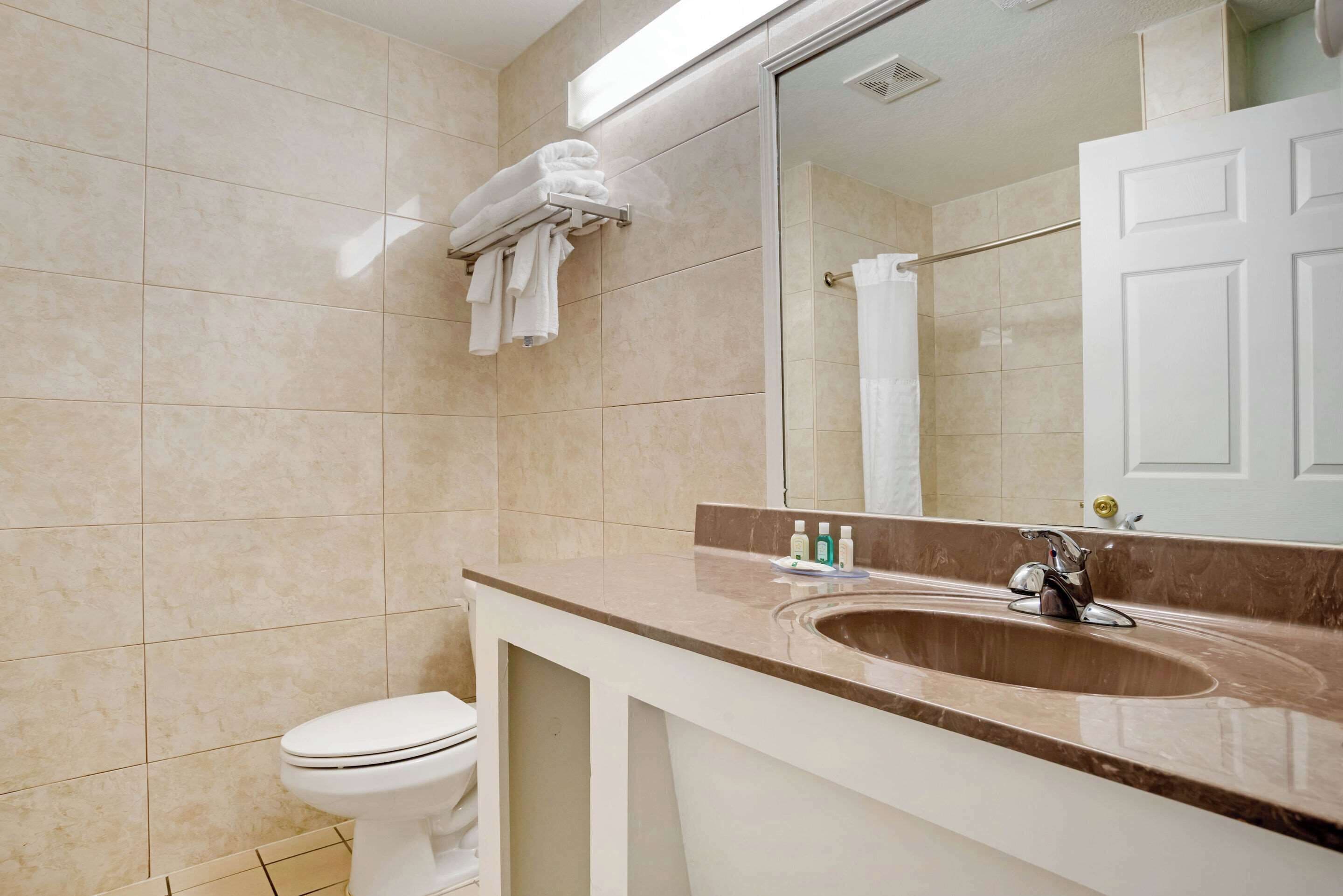 Ein Badezimmer mit Toilette, Waschbecken inklusive Spiegel und Handtuchhalter.