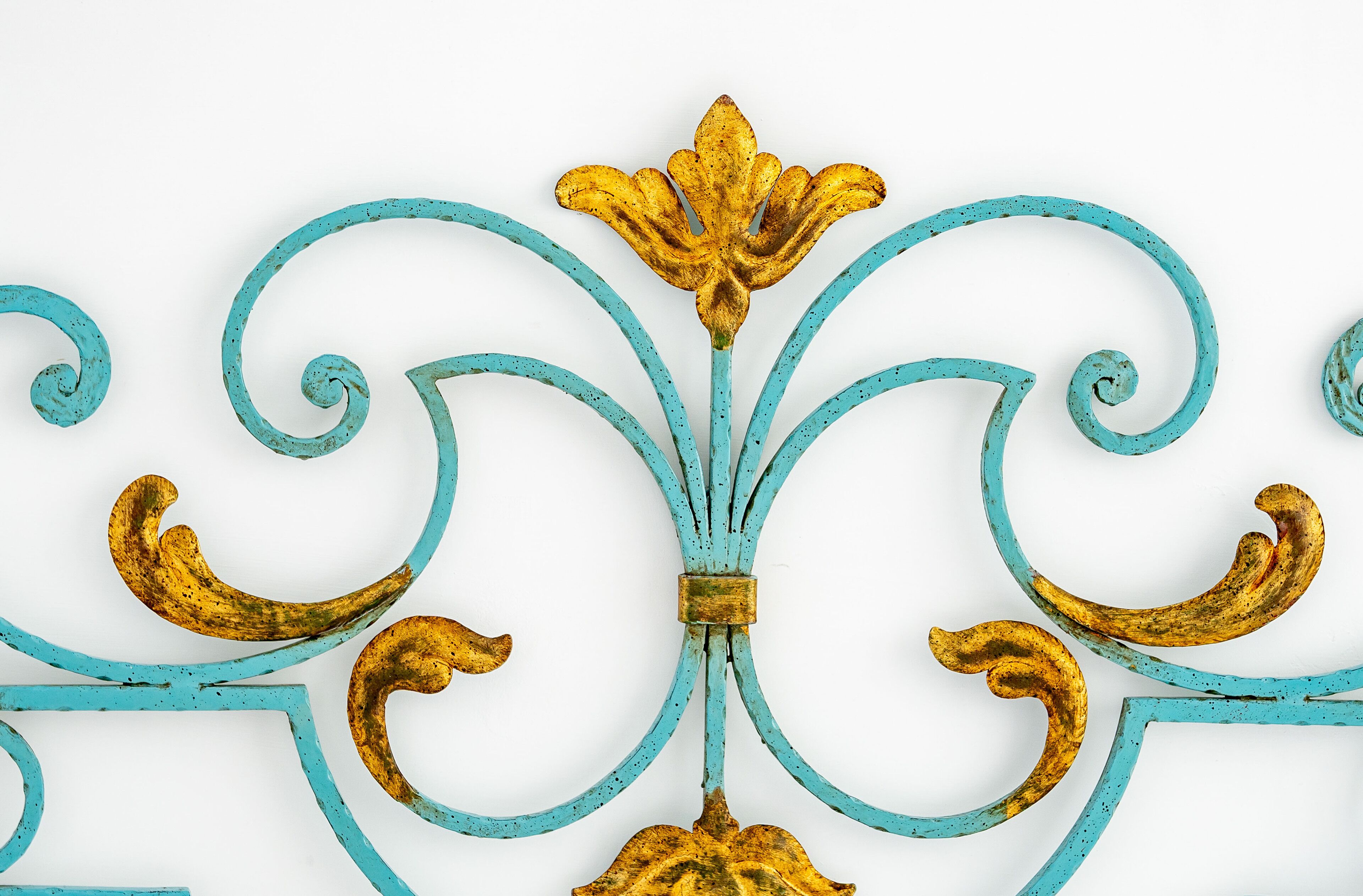 Une clôture décorative en métal, ornée d’un motif floral et agrémentée d’un élément central doré.
