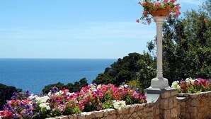 Una pared de piedra con una columna blanca que sostiene una maceta.