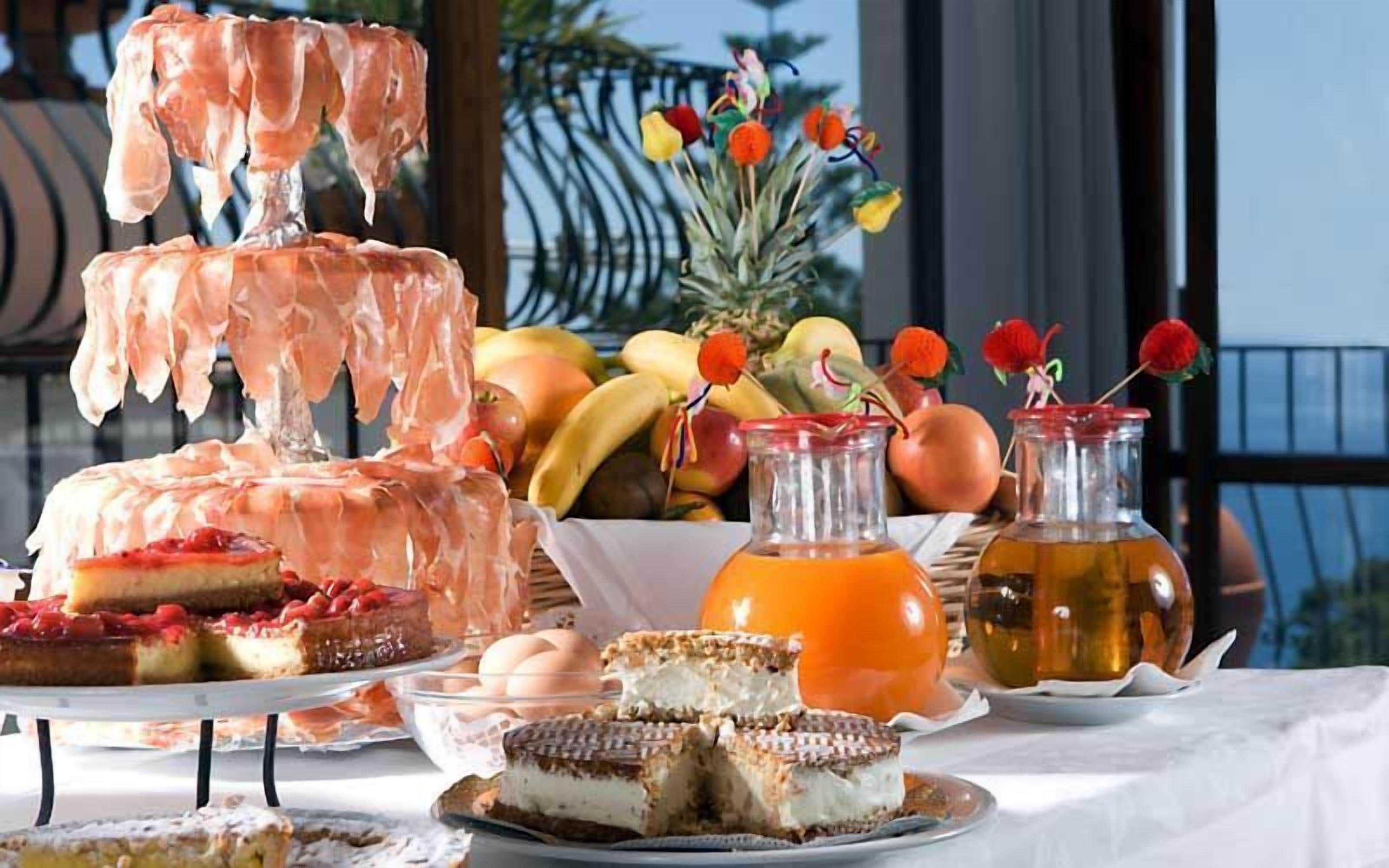 Una mesa con diversos postres, frutas y bebidas.