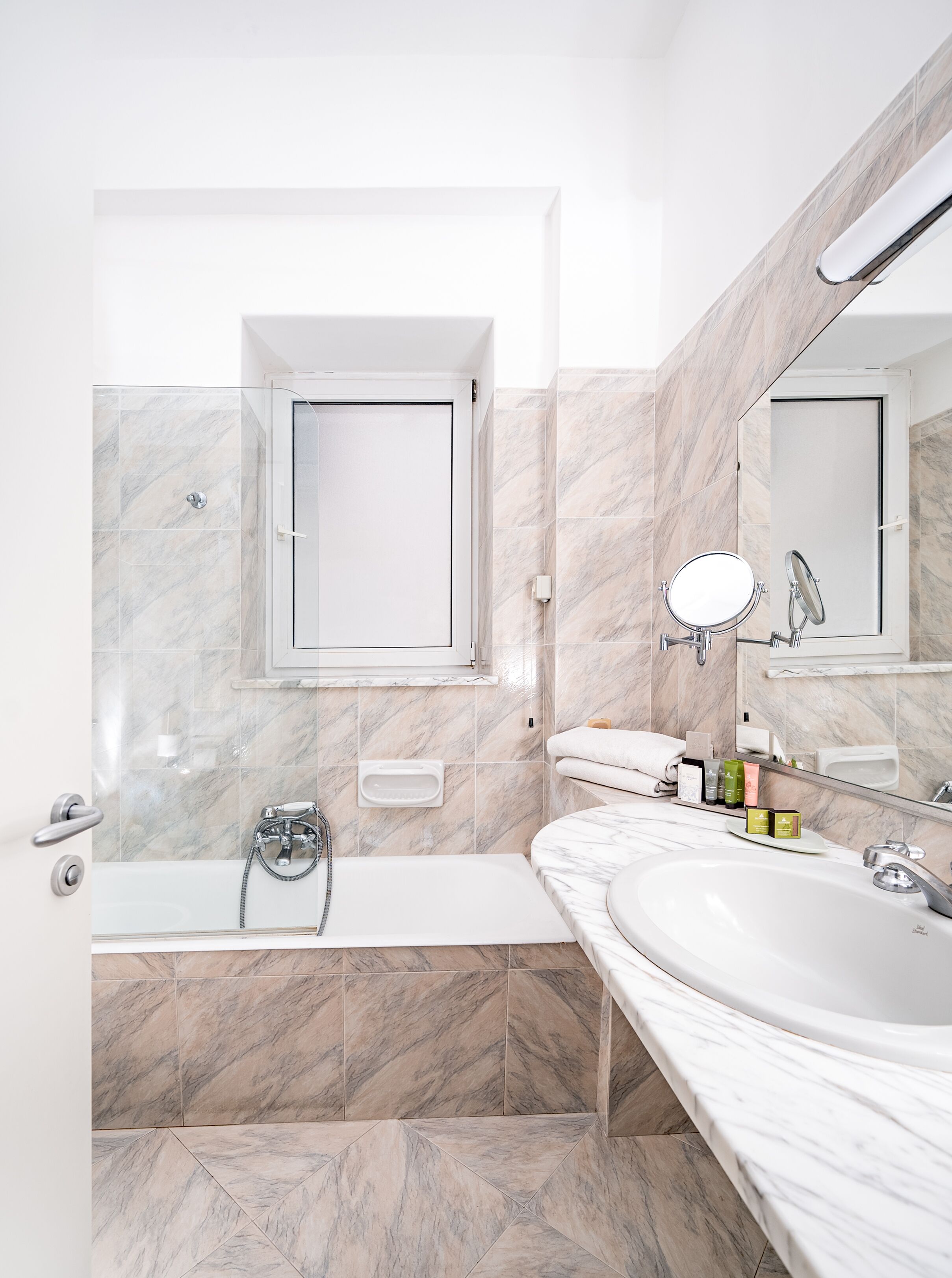 Une salle de bain moderne avec une baignoire, un grand miroir et un meuble-lavabo.