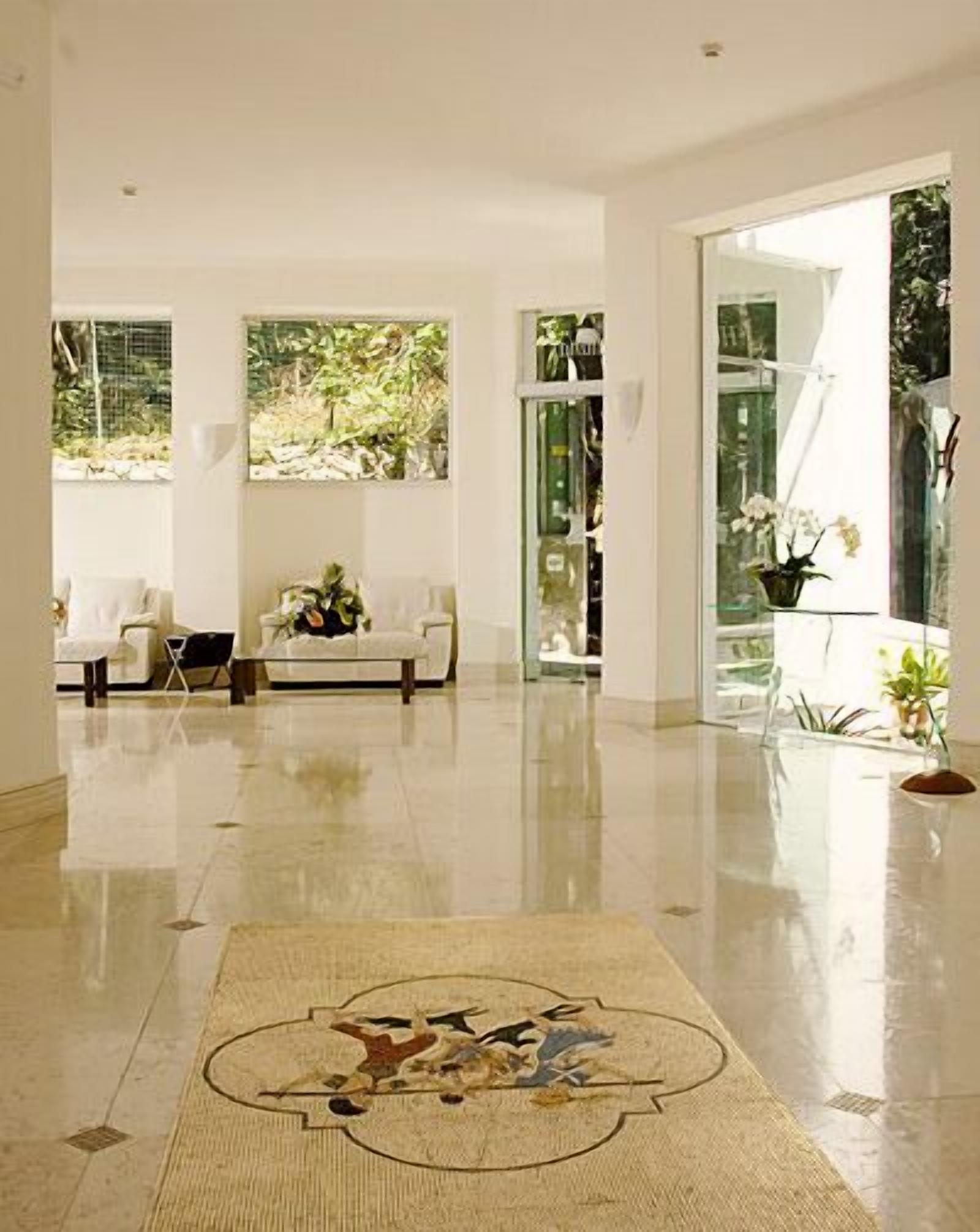 A spacious room with a polished floor, a sofa, and a rug with a bird design.