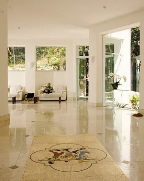 A spacious room with a polished floor, a sofa, and a rug with a bird design.