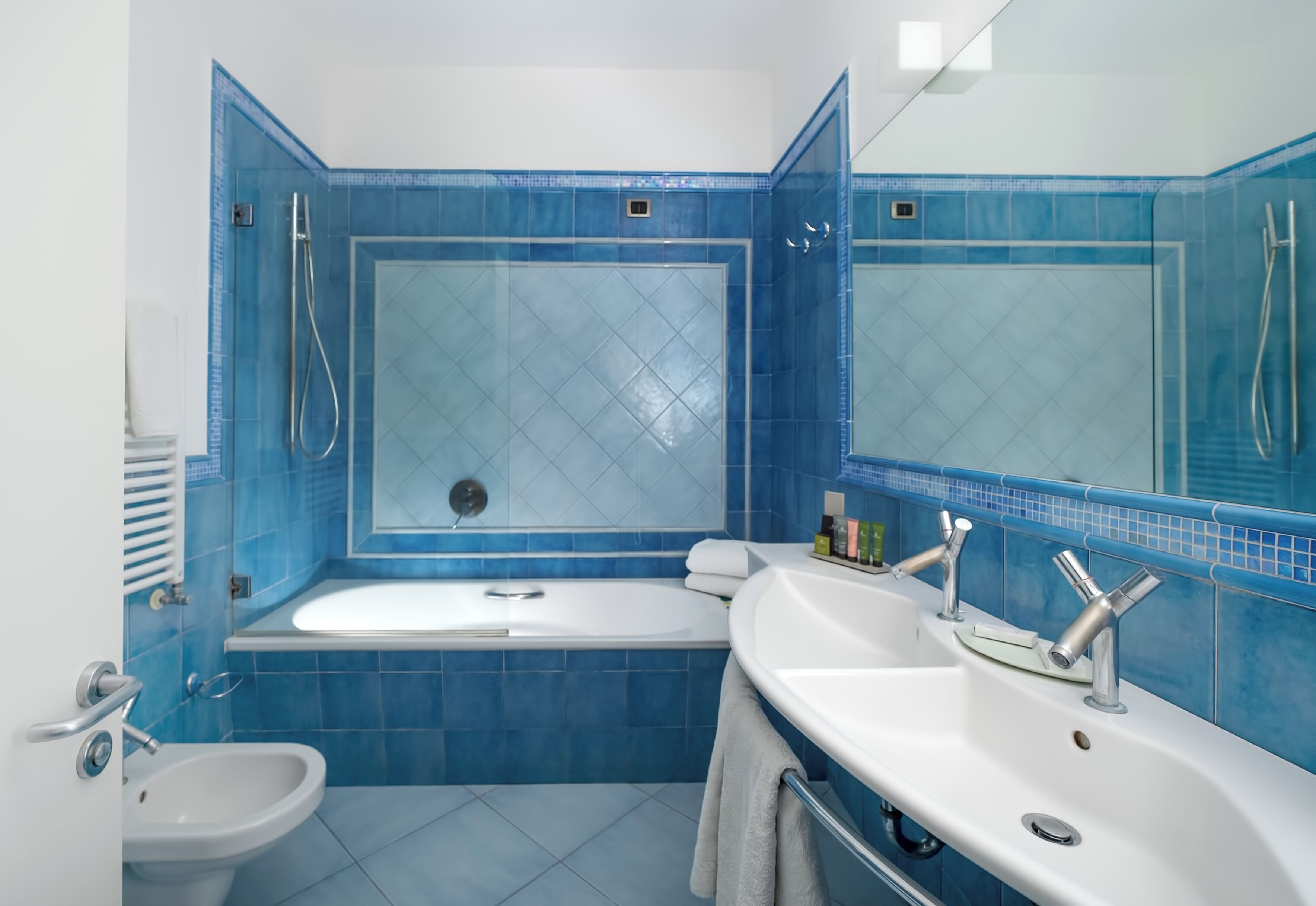 Un baño con bañera, dos lavamanos, un bidé y un espejo.