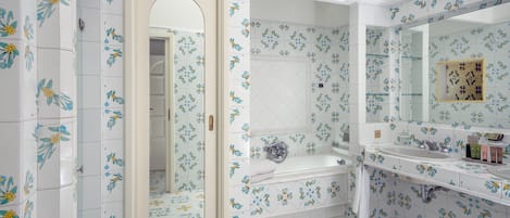 A bathroom with floral tile patterns, a bathtub, a sink, and a mirror.