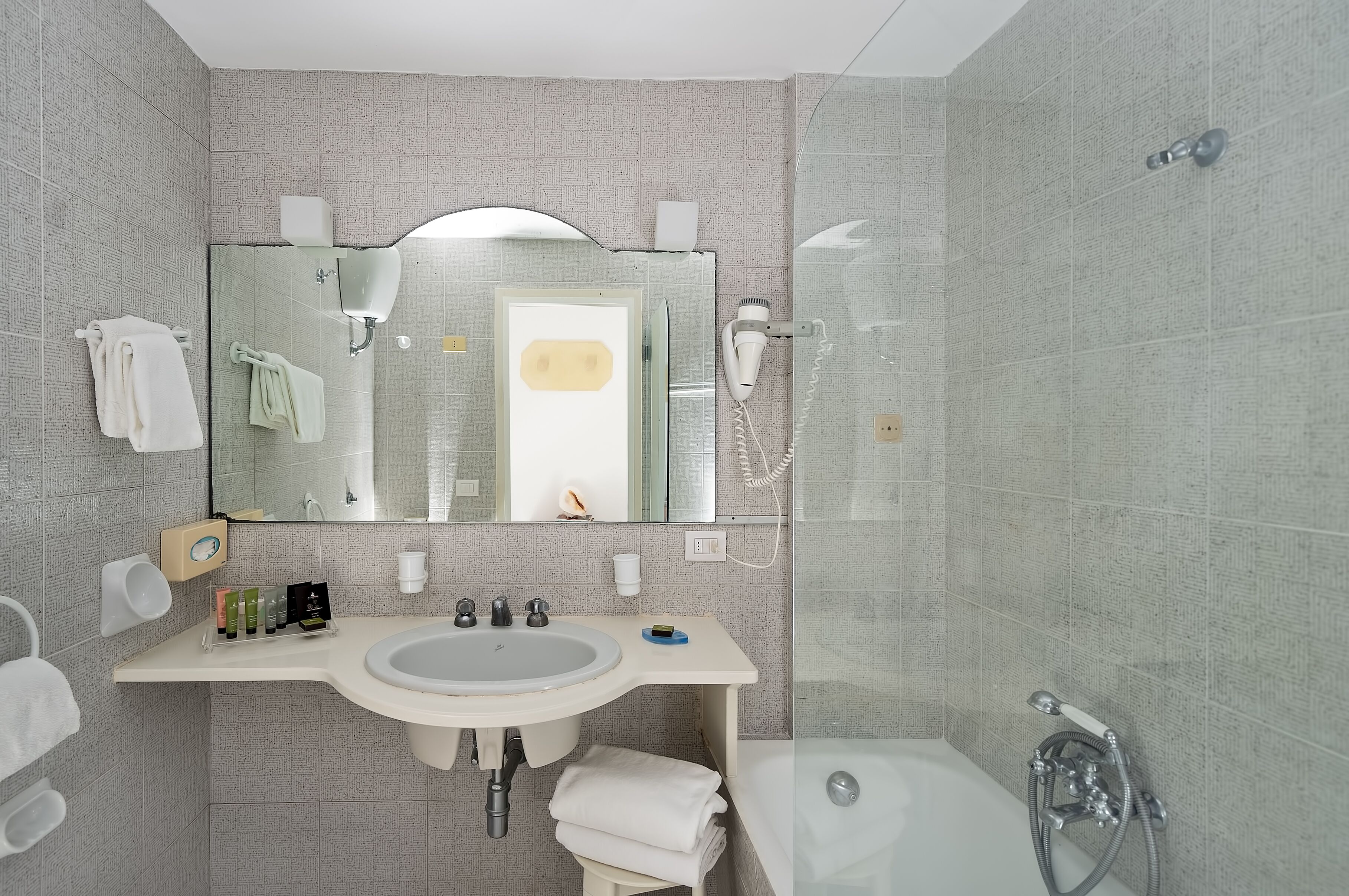 A modern bathroom with a large mirror, a sink, a toilet, and a shower.