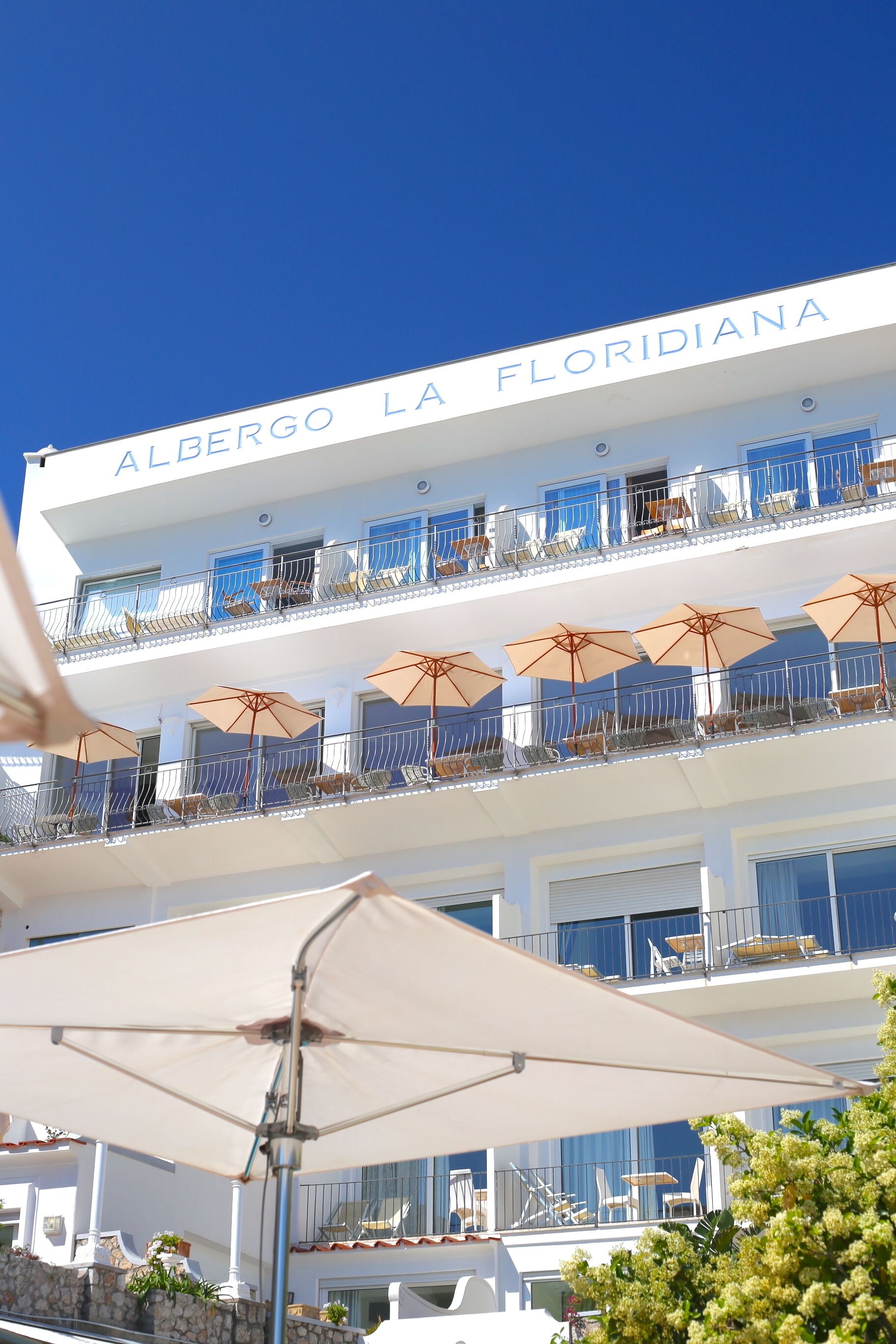 A hotel with balconies, outdoor seating, and umbrellas.
