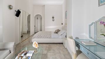 A bedroom with a bed, a glass coffee table, a dresser, and a mirror.