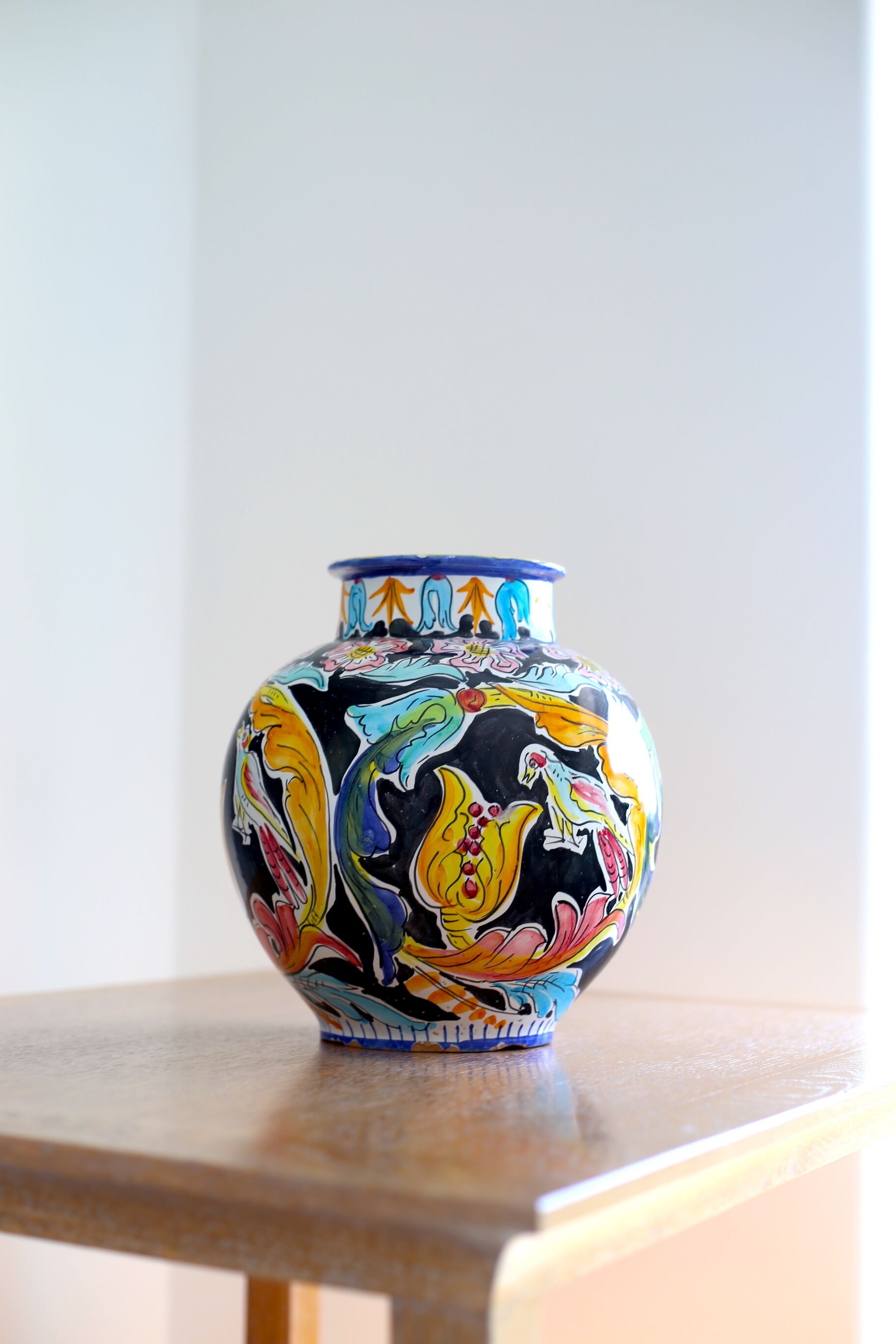 Un jarrón colorido con diseño floral sobre una superficie de madera.