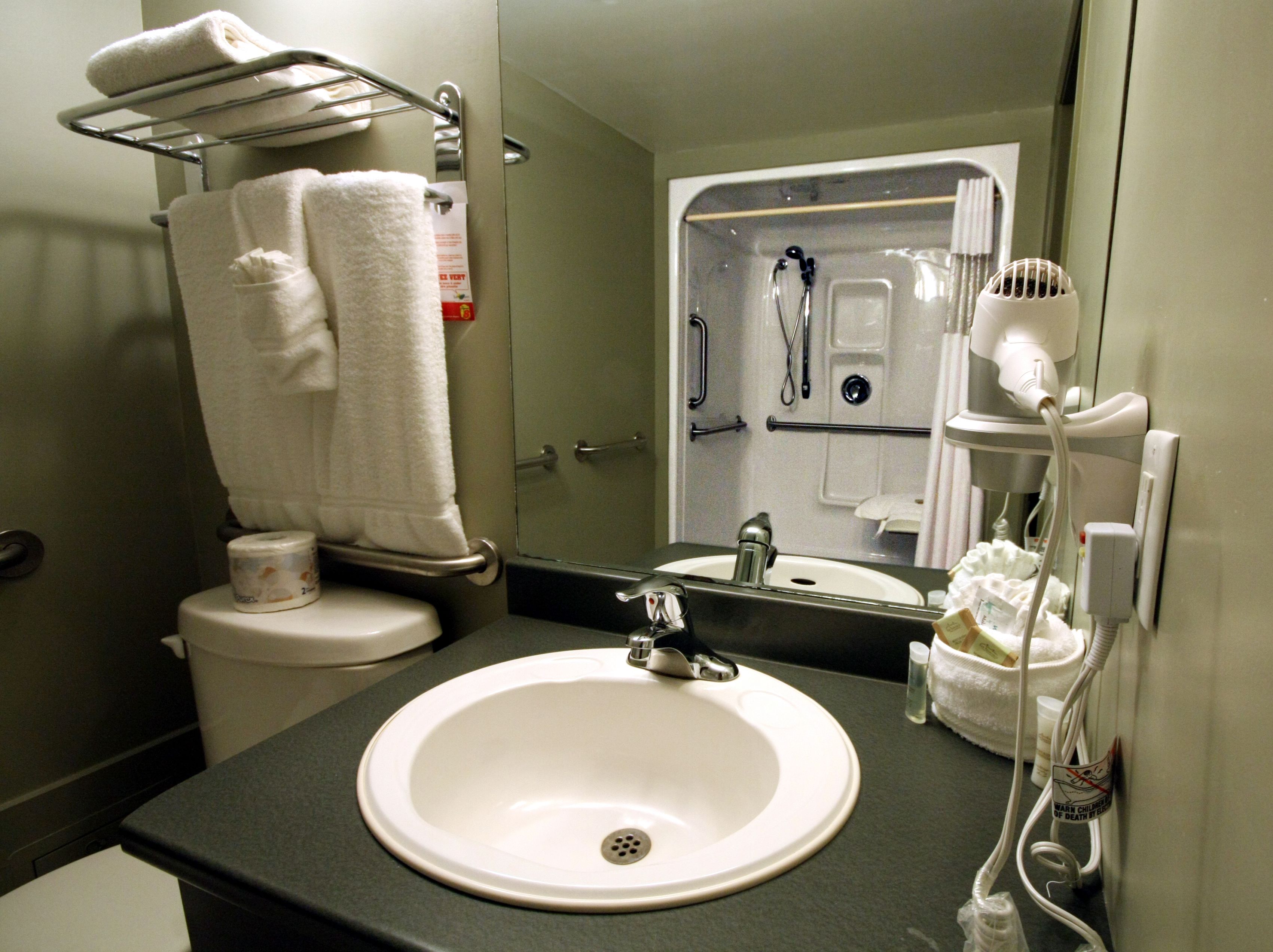 A bathroom with a white sink, a mirror, a towel rack, and a shower area.
