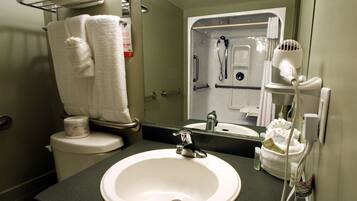 A bathroom with a white sink, a mirror, a towel rack, and a shower area.