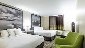 Une chambre d’hôtel avec deux lits, un bureau, une chaise et une grande fenêtre avec des rideaux.