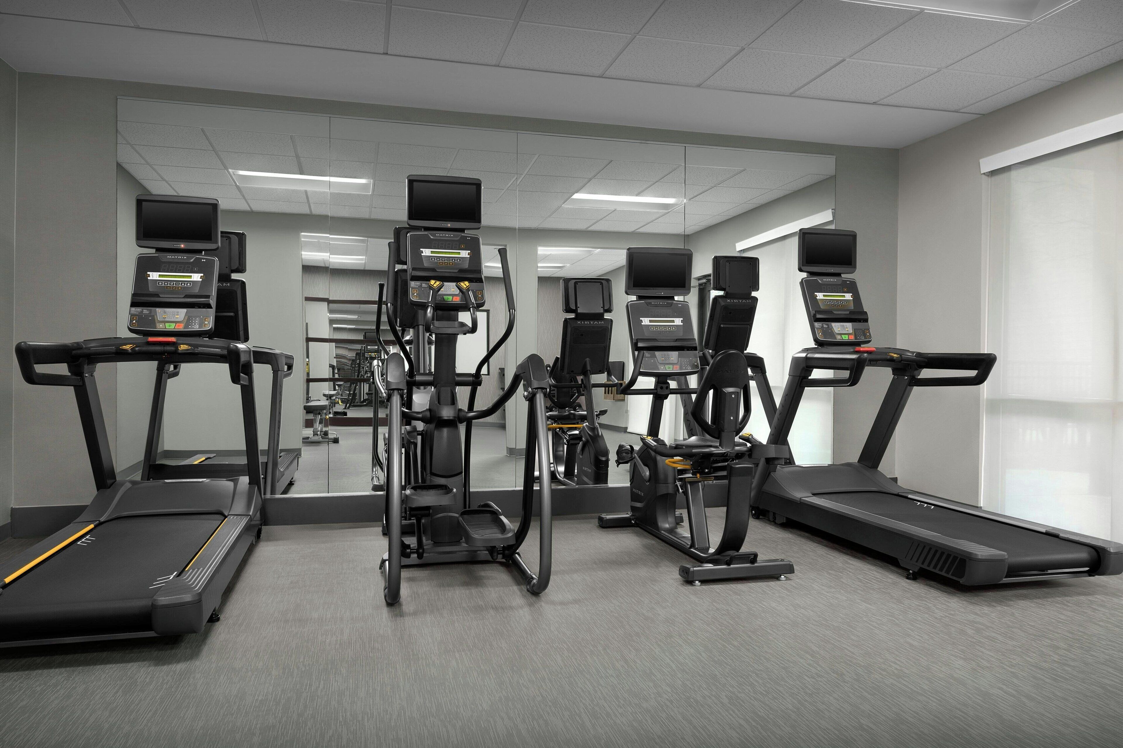 Un gimnasio con cintas de correr, elípticas y equipo de pesas.