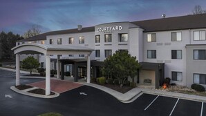 Un hotel Courtyard by Marriott con entrada cubierta, aparcamiento y zona ajardinada.
