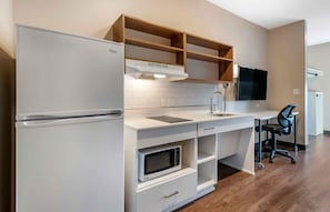 A modern kitchen with a built-in microwave, a refrigerator, wooden shelves, a sink, and a flat-screen TV mounted on the wall. - Extended Stay America Premier Suites San Francisco Belmont (Belmont)