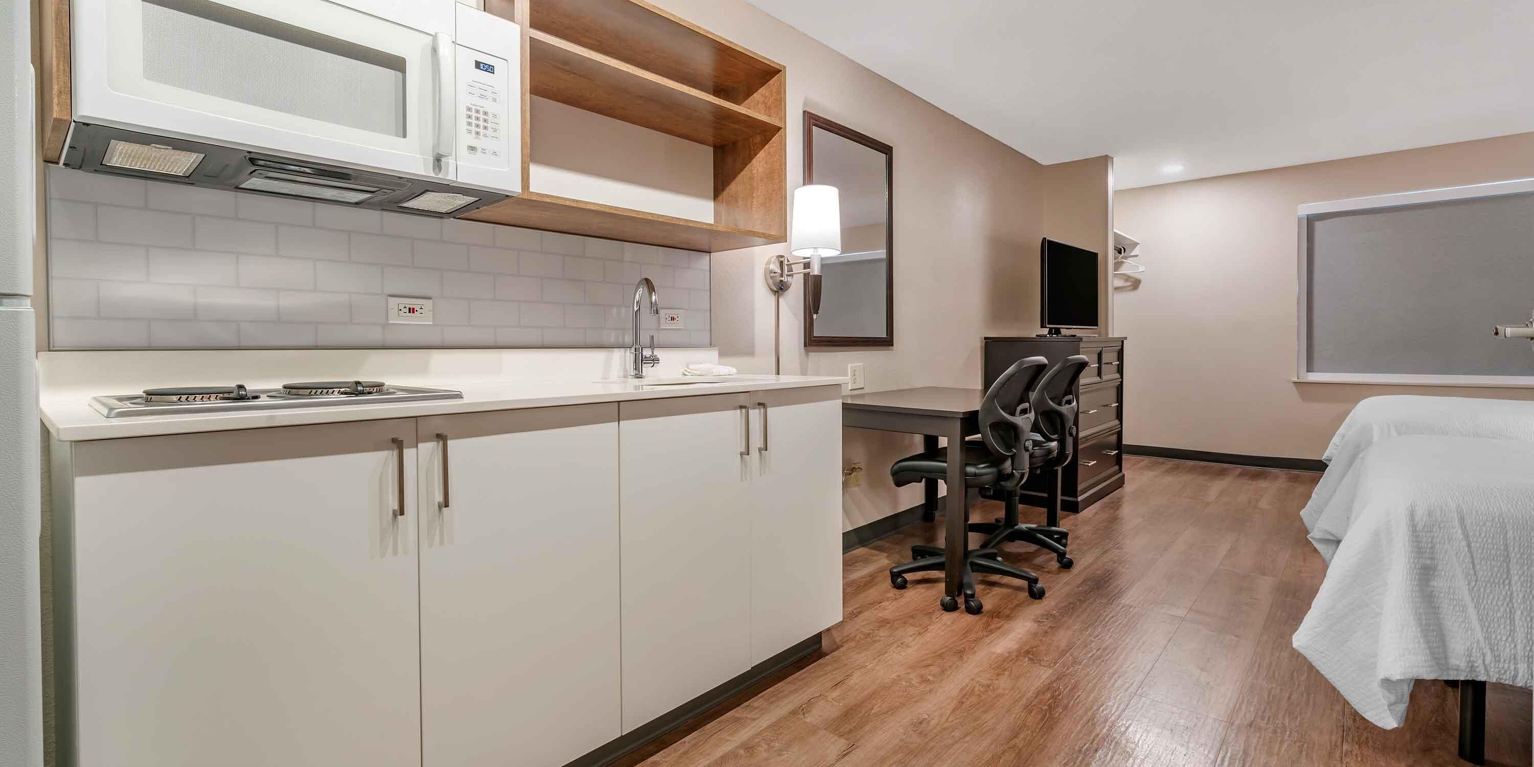 A modern kitchen with a microwave, sink, and stove. There is a dining area with a table and chairs.
