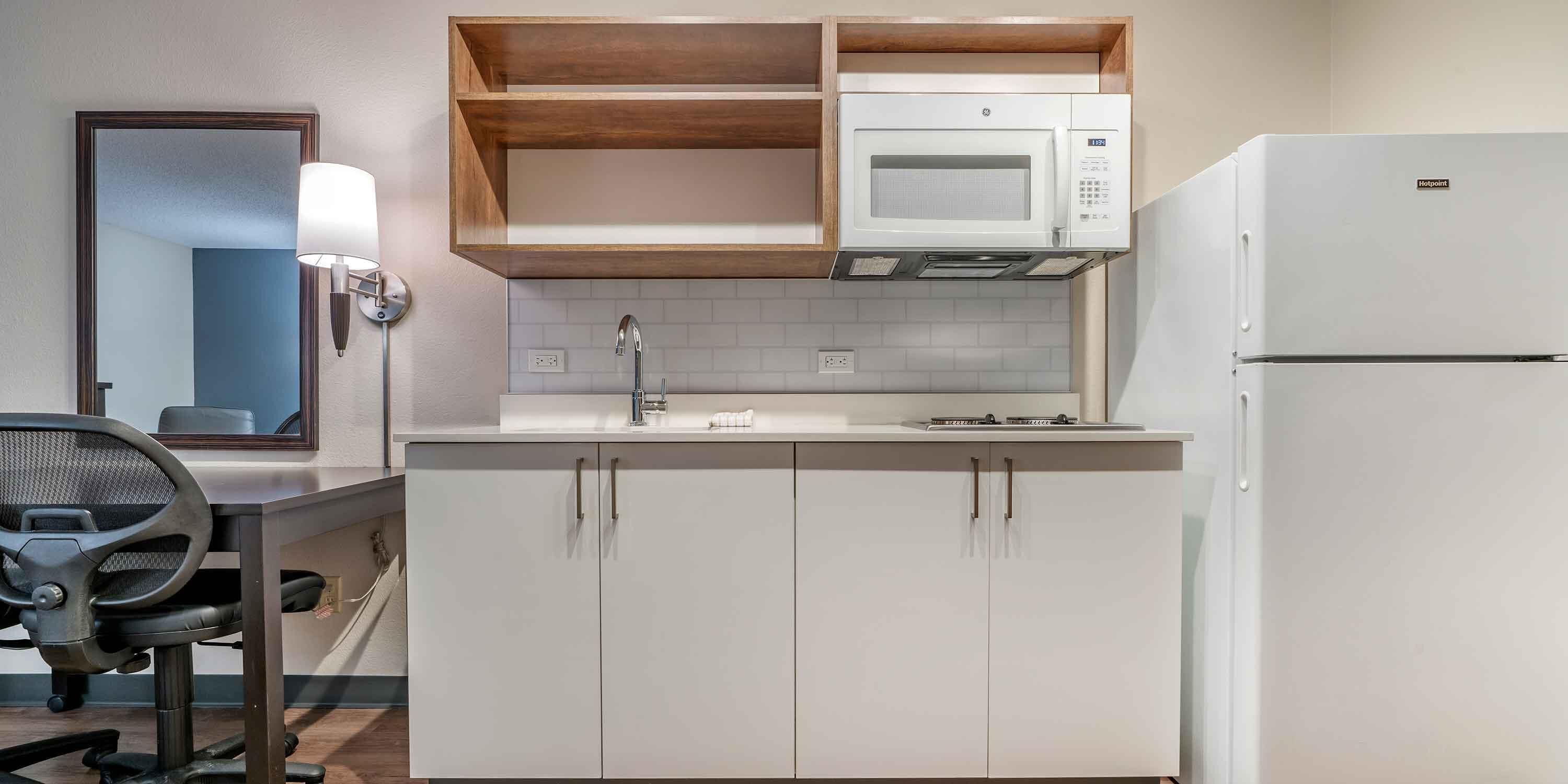 A compact kitchen with white cabinets, a microwave, and a refrigerator.