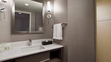 A modern bathroom with a large mirror, a sink, and a towel rack.