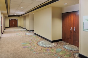 A hotel corridor with carpeted floors, wooden doors, and a sign indicating room availability. - Holiday Inn Grand Rapids Airport by IHG (Grand Rapids)