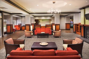 A hotel lobby with a central seating area, a reception desk, and a fireplace. - Holiday Inn Grand Rapids Airport by IHG (Grand Rapids)