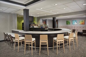 A bar area with a curved counter, multiple chairs, and a carpeted floor. - Holiday Inn Grand Rapids Airport by IHG (Grand Rapids)