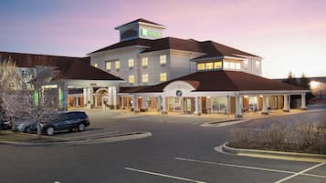 Un hotel Holiday Inn con estacionamiento y acceso al edificio.