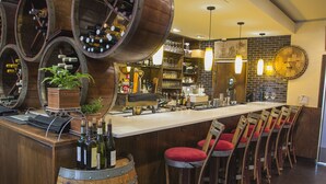 A bar area with wooden barrels, a long counter, and red cushioned stools. - Newbury Guest House (Boston)