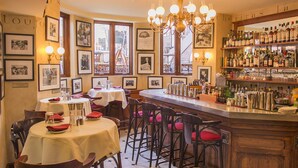 A restaurant interior with round tables, bar area, and framed pictures on the walls. - Newbury Guest House (Boston)