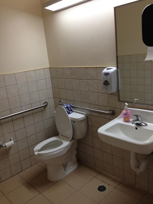 A bathroom with a toilet, a hand dryer, a sink, and a mirror. - Super 8 by Wyndham Ava (Ava)