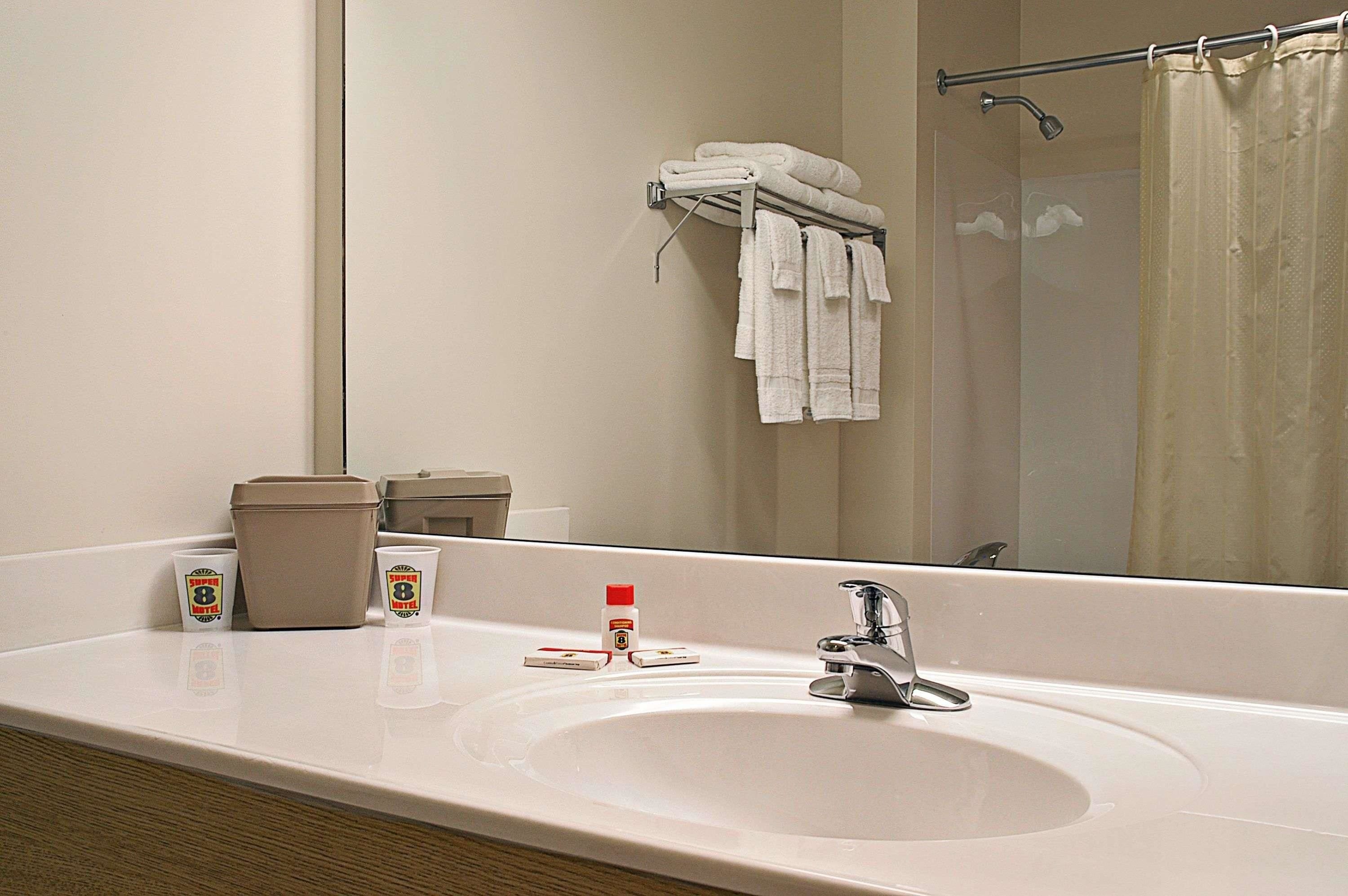 Un baño de hotel con un espejo grande, un lavamanos y un perchero para toallas.