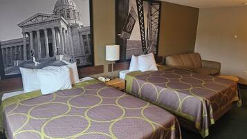 Ein Hotelzimmer mit zwei Betten, einem Nachttisch, einer Lampe und einem großen gerahmten Bild eines historischen Gebäudes.