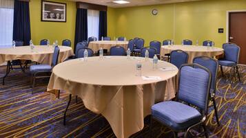 A conference room with multiple round tables, each with chairs and water bottles.