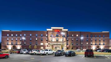 Un hotel con fachada de ladrillo, varios espacios de estacionamiento y una entrada bien iluminada.