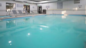 Une piscine intérieure à l’eau claire, dotée de chaises longues et de panneaux d’information fixés aux murs.