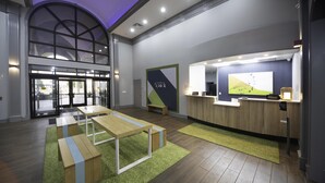 Un hall d’hôtel moderne avec un comptoir d’accueil, un espace salon et de grandes fenêtres.