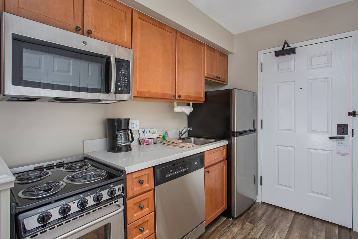 A kitchen with a stainless steel stove, microwave, dishwasher, and refrigerator.