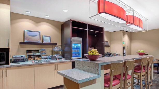 A modern kitchen with a built-in refrigerator, a microwave, and a coffee machine. There are wooden chairs and a bar counter with a bowl of fruit. - TownePlace Suites by Marriott Knoxville Cedar Bluff (Knoxville)