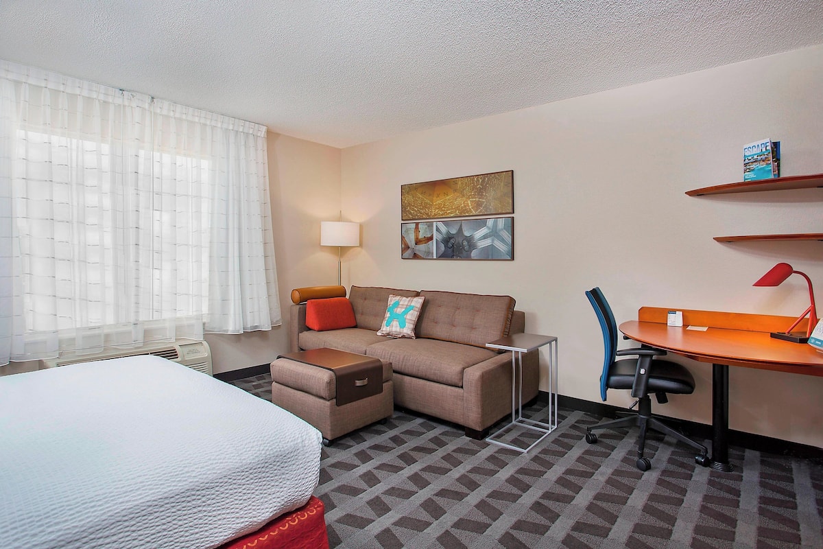 A hotel room with a bed, a sofa, a desk, and a chair.
