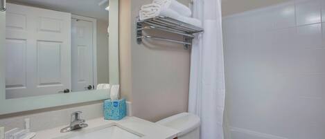 Un baño con lavabo, espejo, toallero y cortina de ducha.