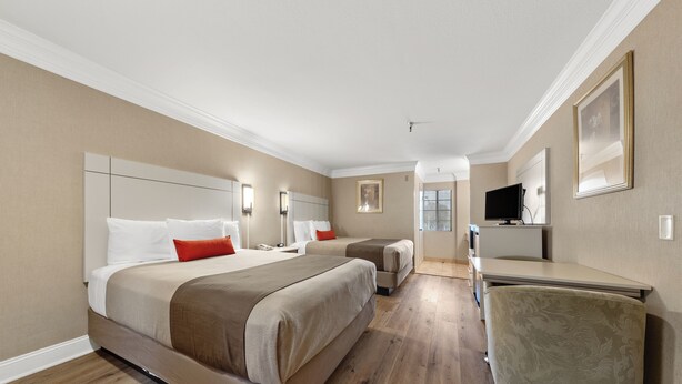 A hotel room with two beds, a desk, a chair, and a television. - Americas Best Value Inn San Clemente Beach (San Clemente)