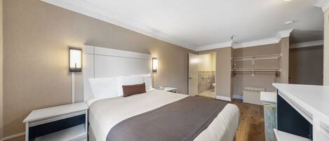 A hotel room with a large bed, bedside tables, a desk, and a walk-in closet.