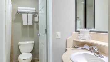 Un baño con inodoro, toallero, lavamanos y espejo.