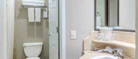 A bathroom with a toilet, a towel rack, a sink, and a mirror.